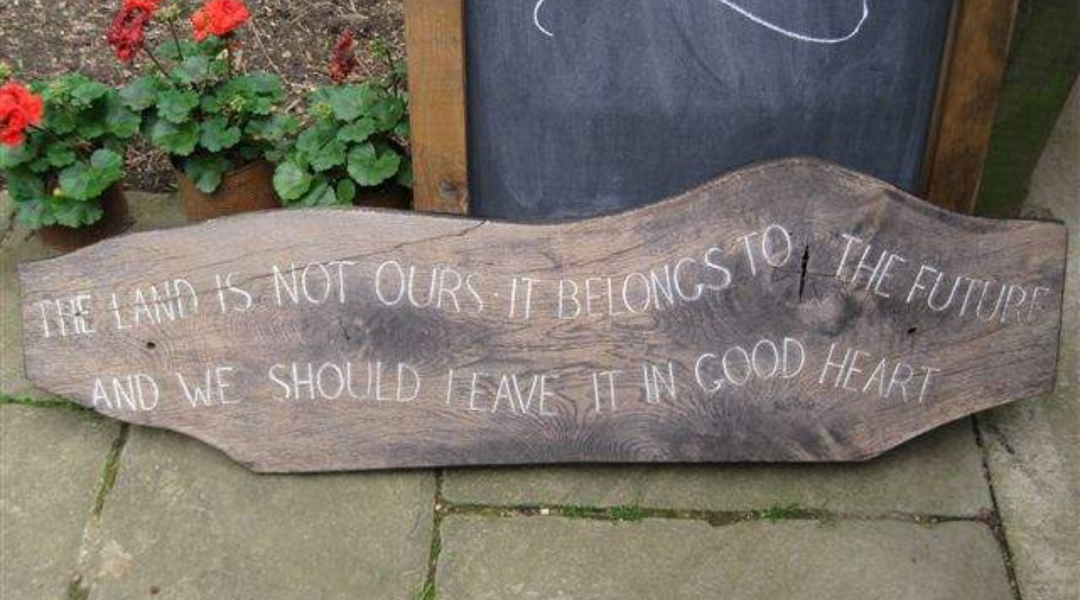 A piece of wood from a tree trunk from Abbey Home Farm. On it the words 'The land is not ours. It belongs to the future and we should leave it in good heart' are painted.