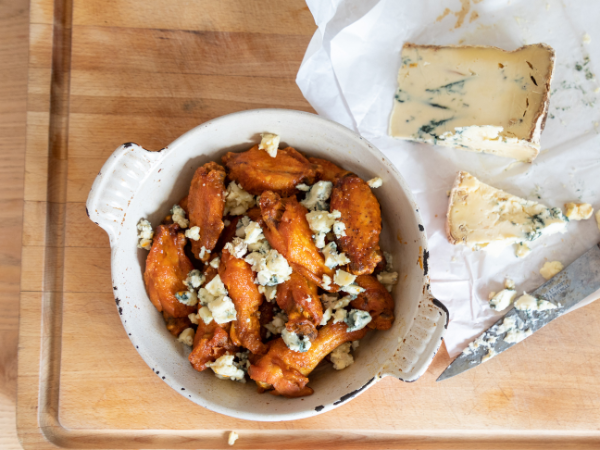 A dish full of hot wings with blue cheese crumbled on top